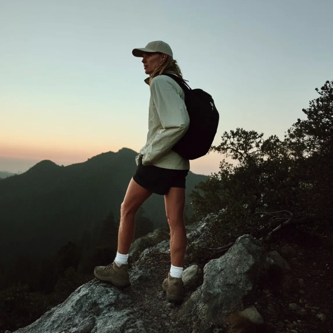 Hiker with a backpack standing on a mountain peak at sunset | Polar Philippines
