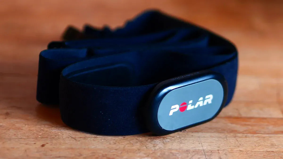Coiled black fabric heart rate sensor chest strap resting on a wooden table | Polar Philippines