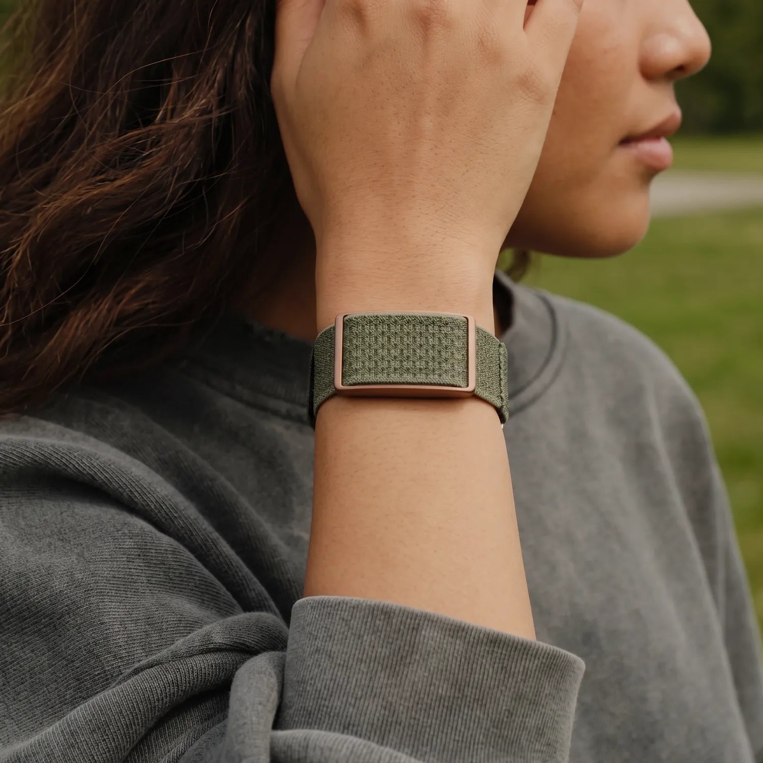 Woman fixing her hair while wearing a heart rate sensor in an open field outdoors | Polar Philippines