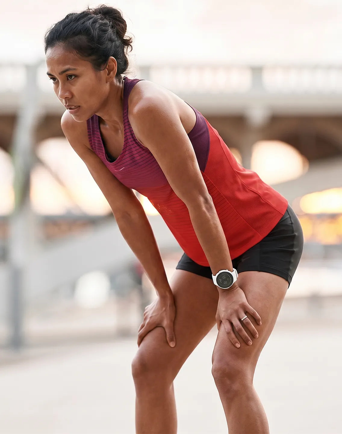 Woman wearing a smartwatch while resting after a run with a blurred outdoor background | Polar Philippines