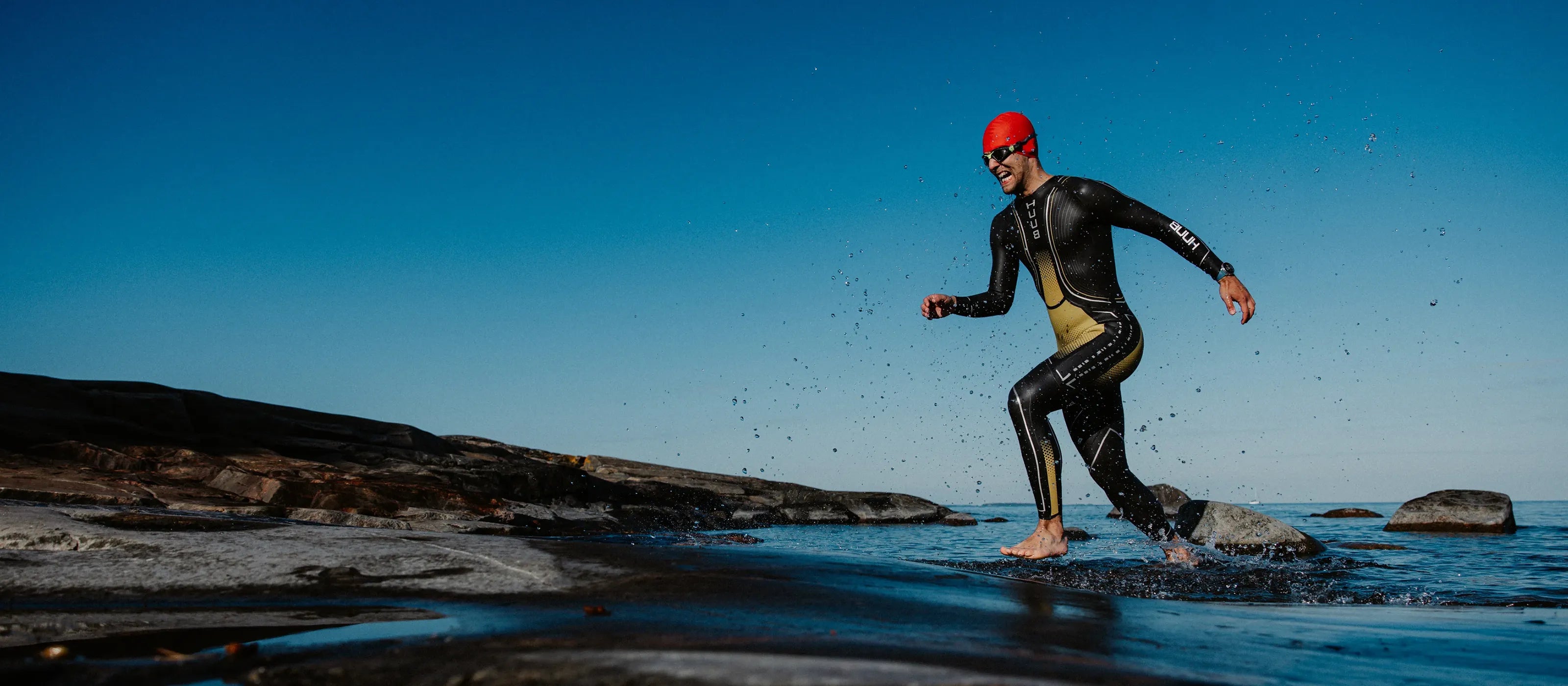 Triathlete running from water in wetsuit during open-water training | Polar Philippines